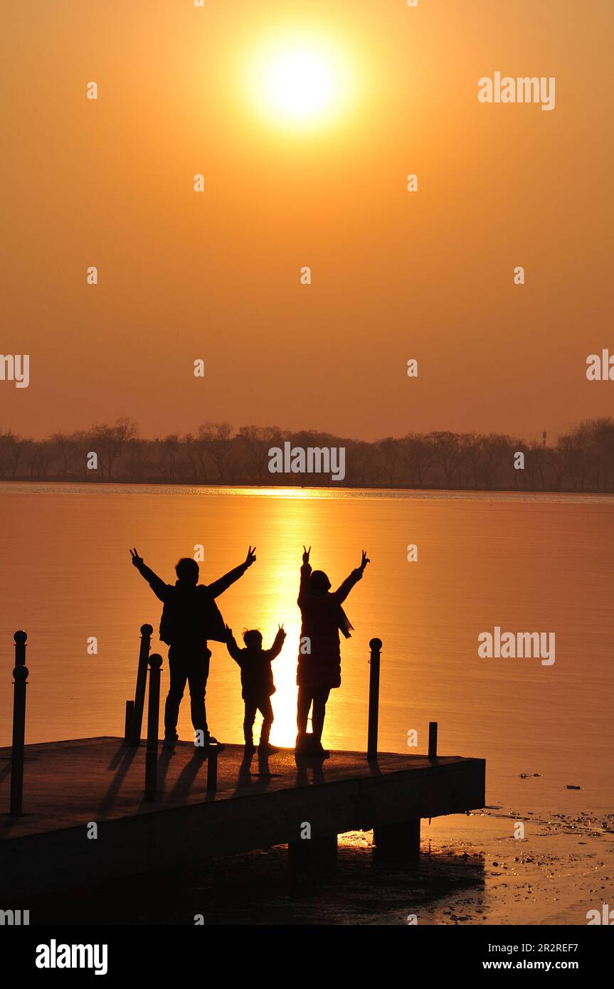 Silhouettes de famille heureuse sur fond de mer, de soleil, de nuages fond sur Orange coucher de soleil sur mer Banque D'Images