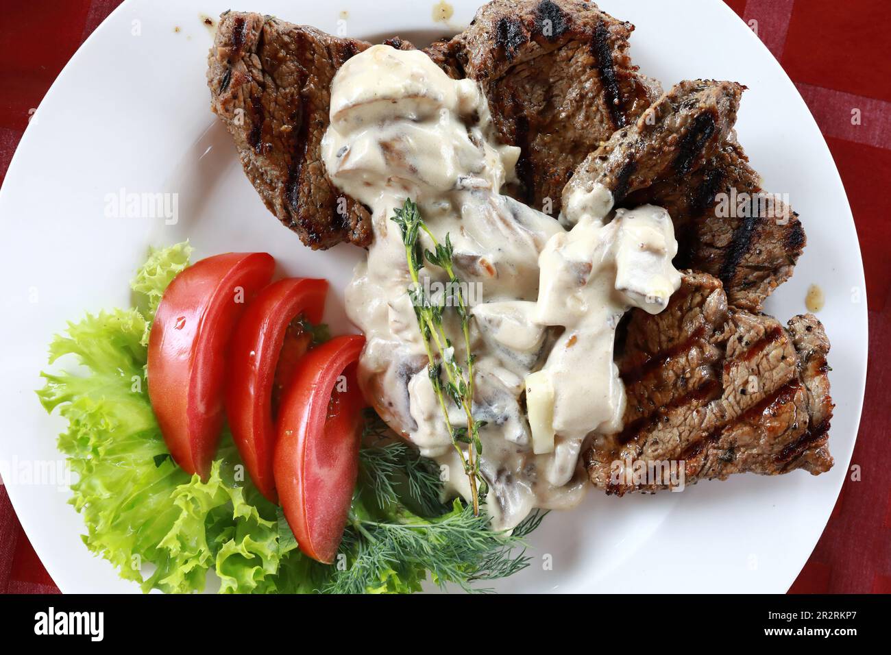 Steak de bœuf avec sauce aux champignons et tomates sur l'assiette du restaurant Banque D'Images