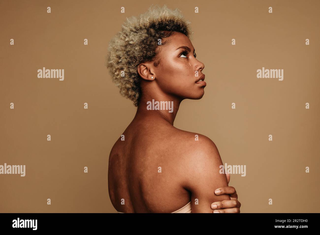 Une jeune femme africaine se tient dans un studio avec une expression émotionnelle des larmes et regardant loin. Authentique et réelle, elle est représentative de Gen Z femi Banque D'Images