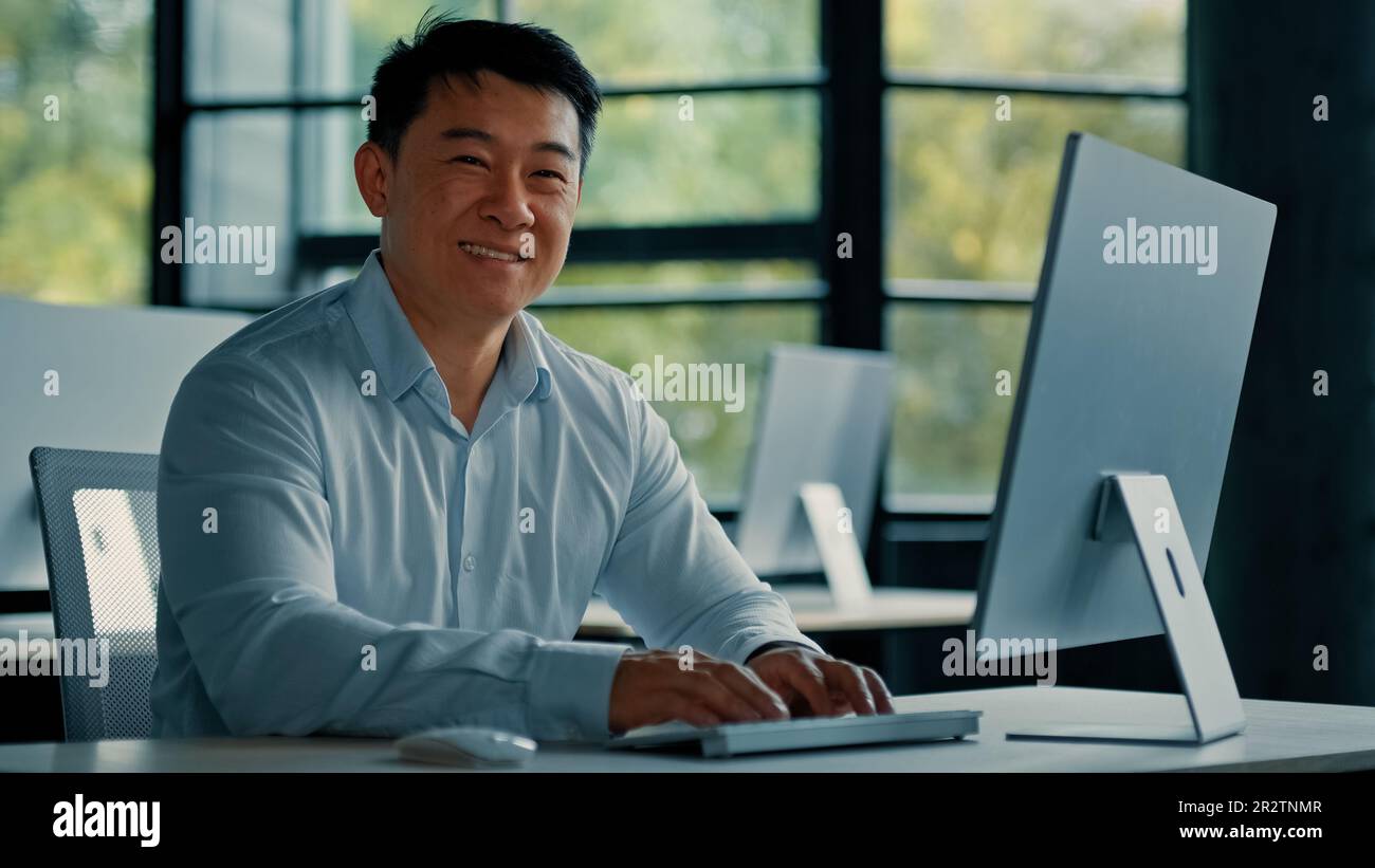 Homme d'affaires asiatique mature travailleur de bureau coréen chinois spécialiste homme travail sur ordinateur développer projet en ligne regarder la caméra sourire confiant. Portrait Banque D'Images