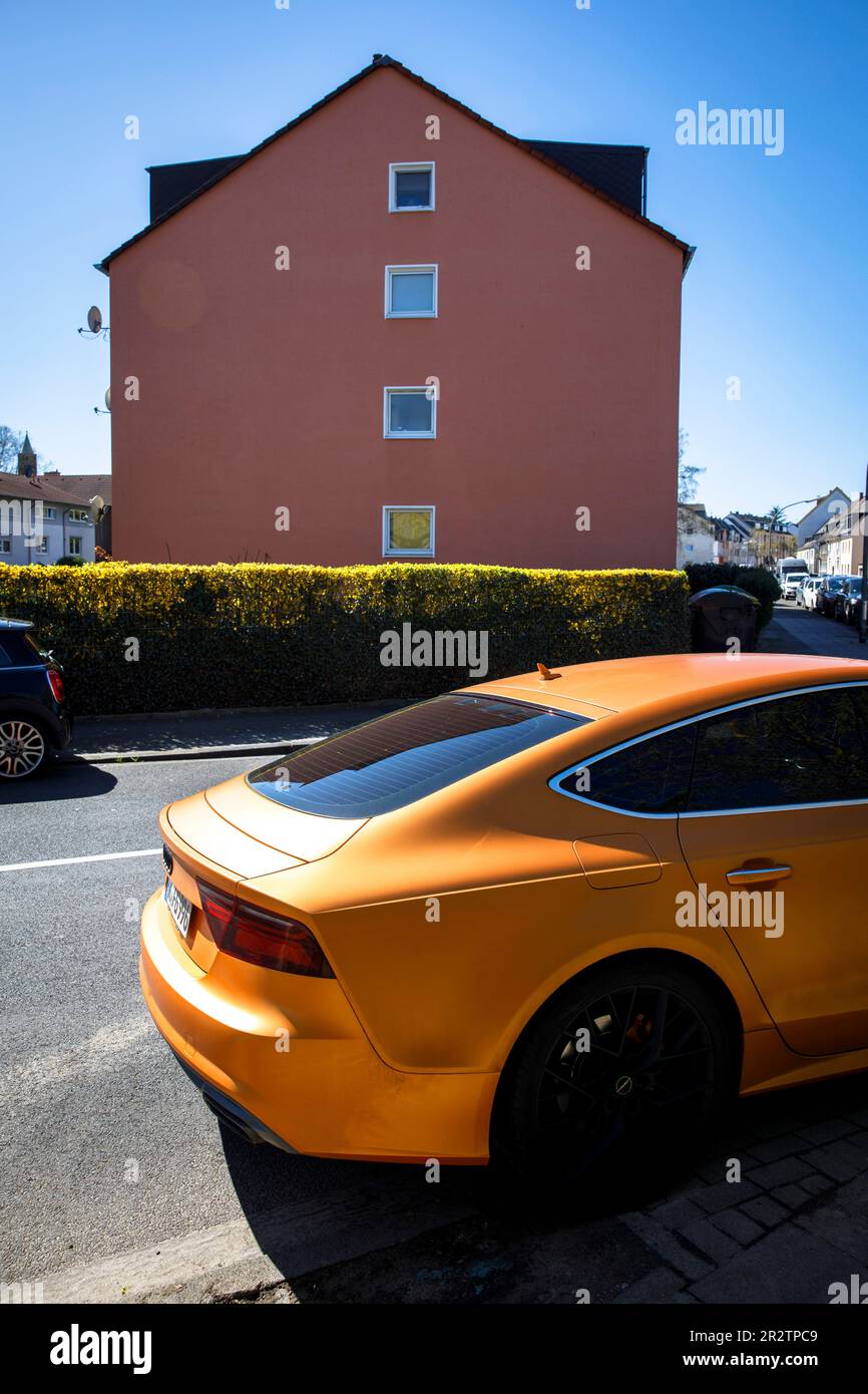 Une Audi A5 Sportback orange est garée en face d'une maison rouge dans le quartier de Niehl à Cologne, en Allemagne. ein orangefarbener Audi A5 Sportback stht vo Banque D'Images