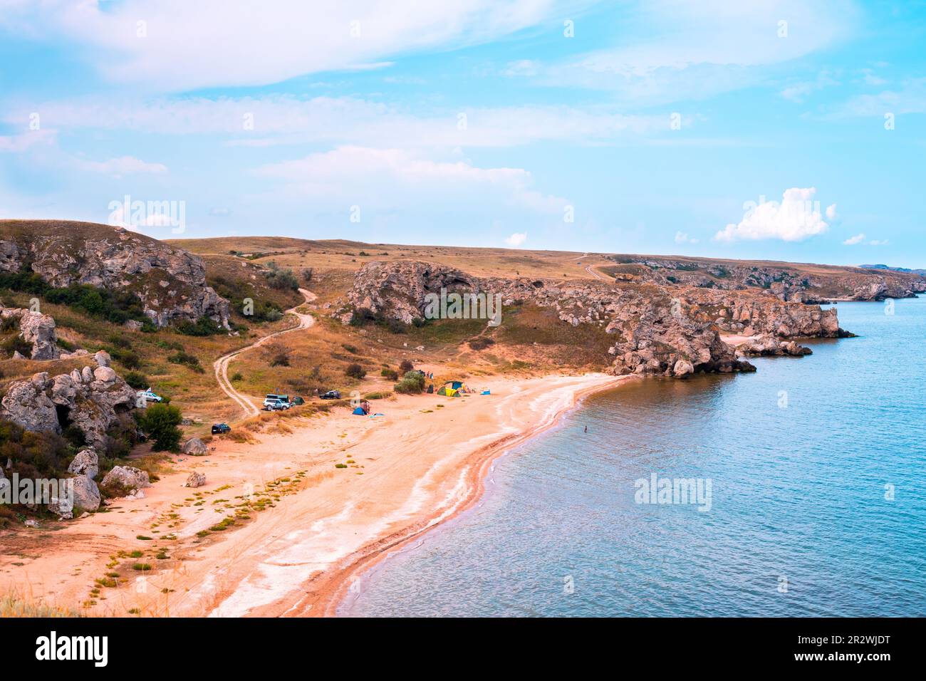 Baie de la mer avec rivage de sable et collines. Les touristes et les voyageurs se reposent sur le rivage dans un camp de tentes. Banque D'Images