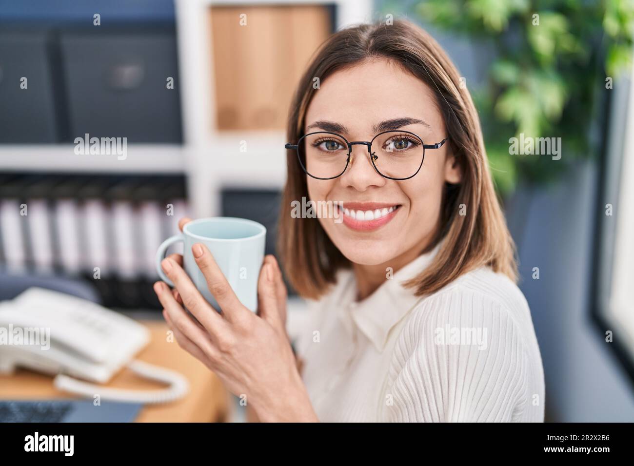 Jeune belle femme hispanique travailleur d'affaires buvant du café au bureau Banque D'Images