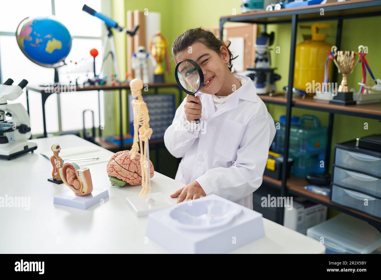 Adorable fille hispanique étudiant scientifique utilisant la loupe dans la salle de classe de laboratoire Banque D'Images