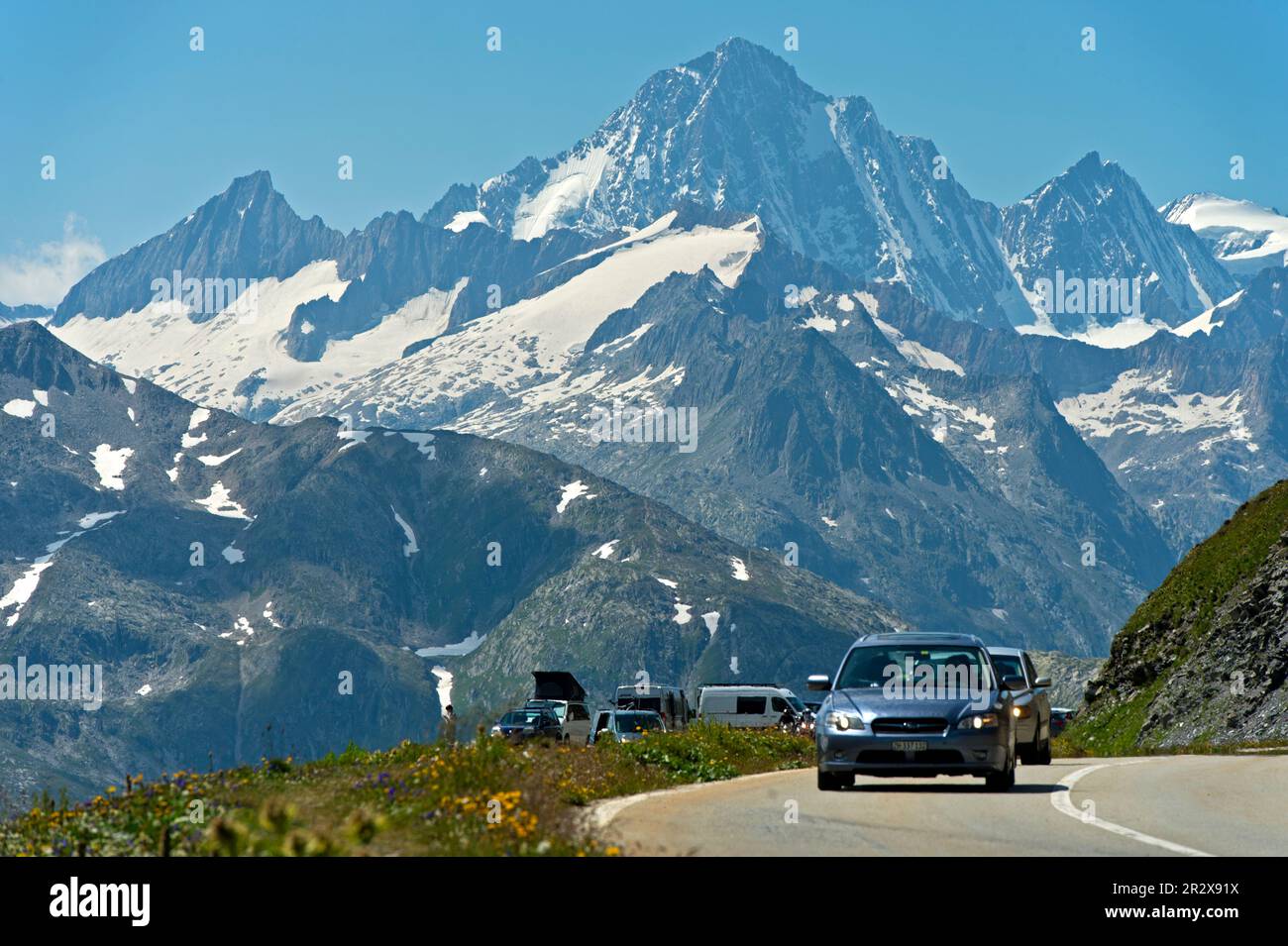 Voitures sur la route de montagne vers le col de Furka, le sommet de Finsteraarhorn derrière, Gletsch, Obergoms, Valais, Suisse Banque D'Images