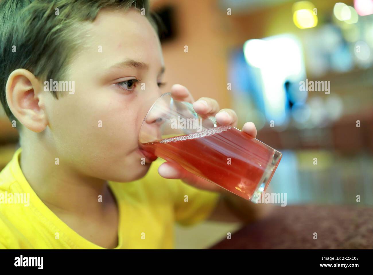Un enfant fatigué boit du jus dans le restaurant Banque D'Images