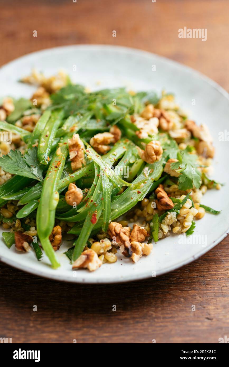 Assiette avec un Freekeh fait maison avec des haricots verts et une salade d'herbes. Banque D'Images