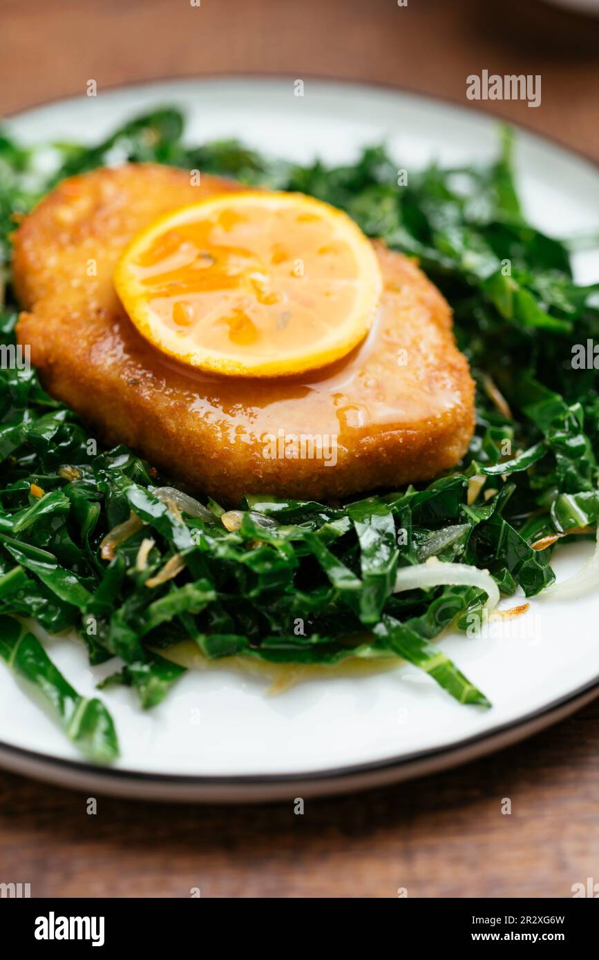 Assiette de Schnitzel végétalien sur chou de savoie sauté avec une sauce à l'orange Chili. Banque D'Images