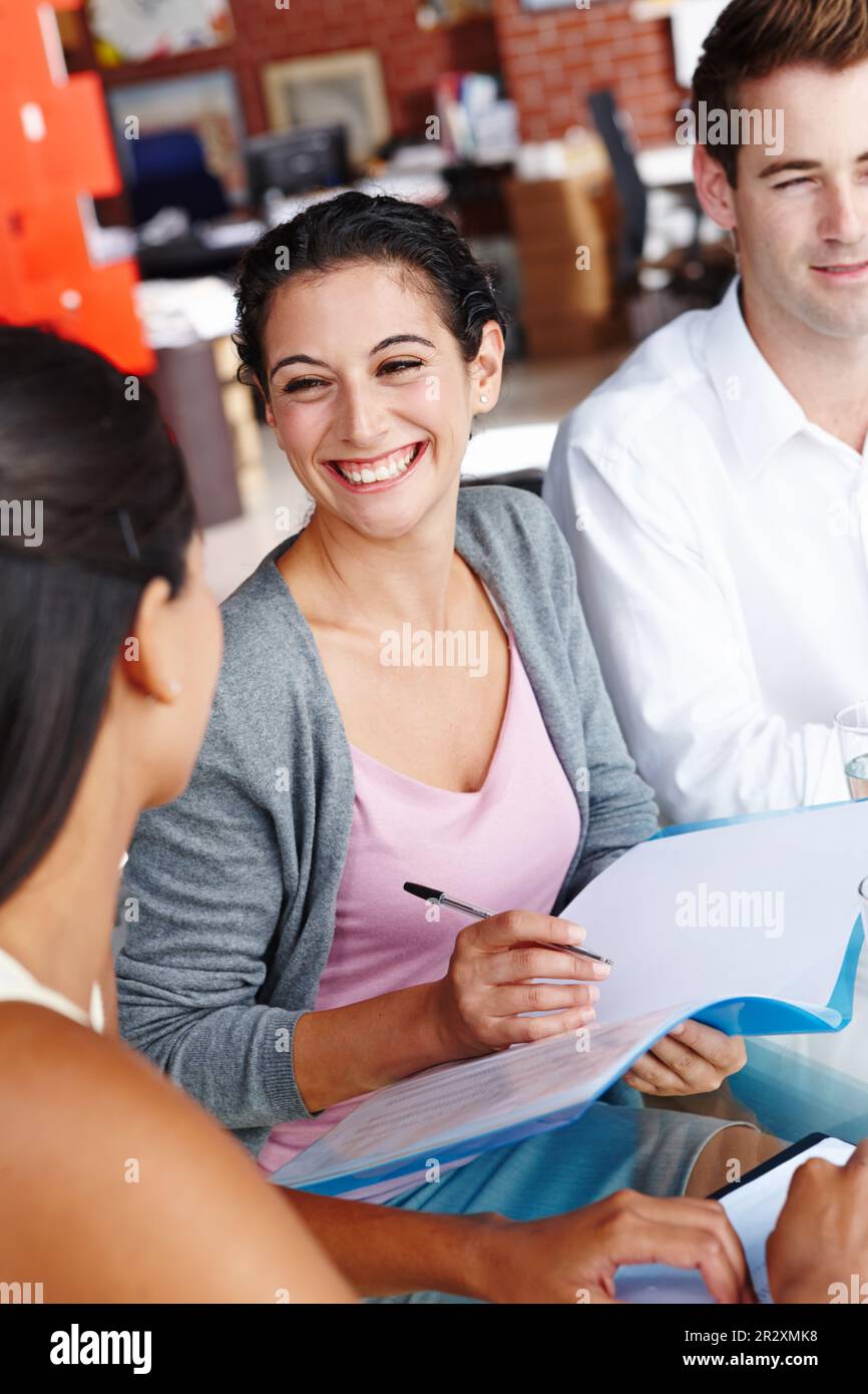 Prendre des notes dans une réunion collaborative. Une équipe heureuse de collègues créatifs remue-méninges autour de la table de la salle de réunion. Banque D'Images