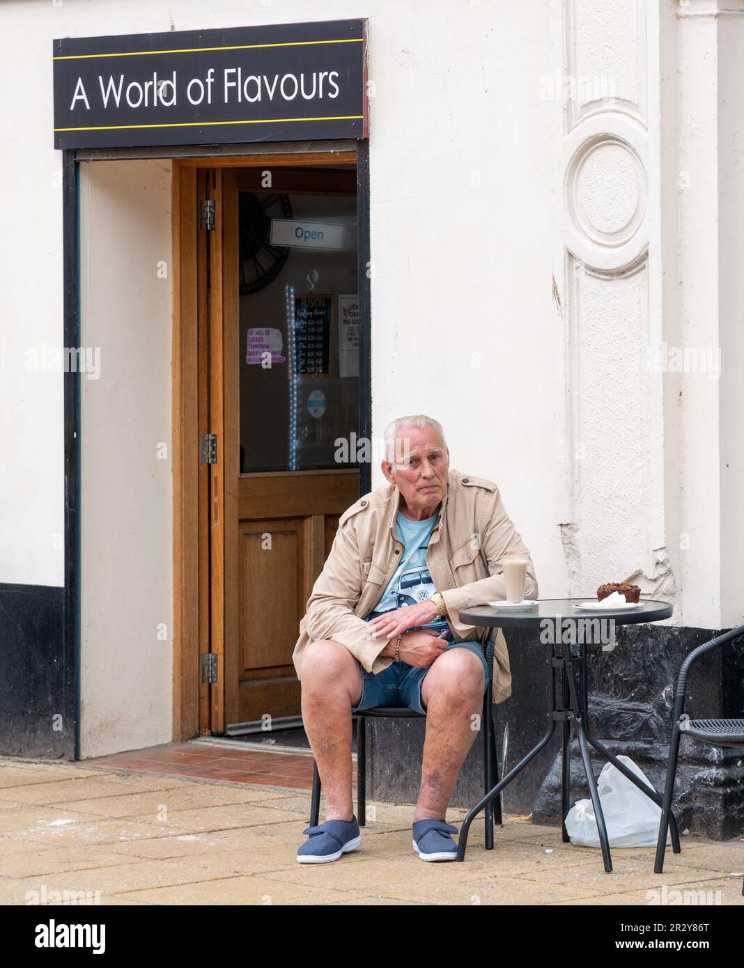 20 mai 2023. High Street, Nairn, Écosse. C'est un homme assis dans un café appelé un monde de saveurs. Banque D'Images