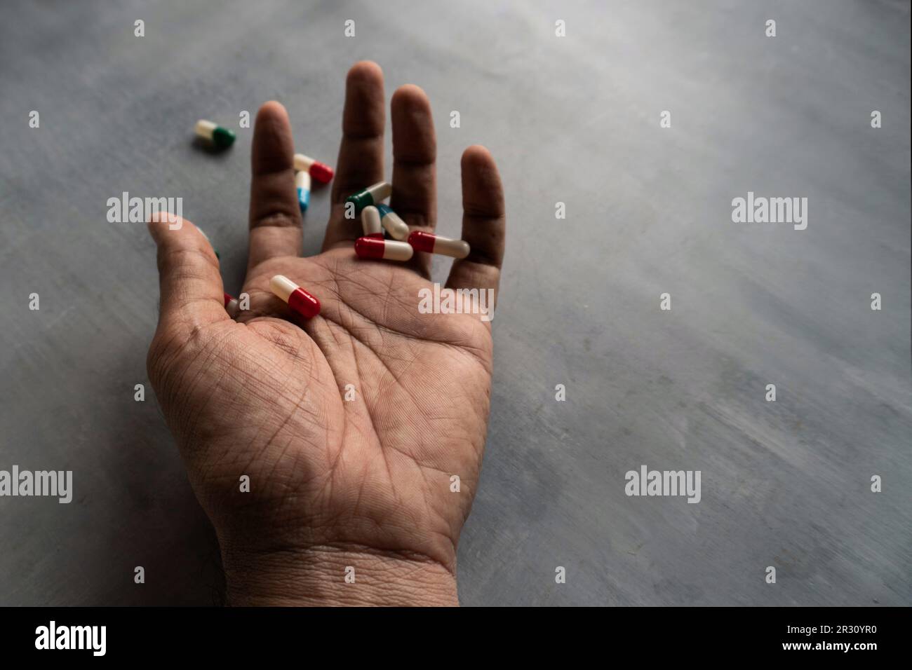 Gros plan de la main et des pilules sur un sol en béton avec espace de copie. Surdose, addict de drogue et concept de suicide Banque D'Images