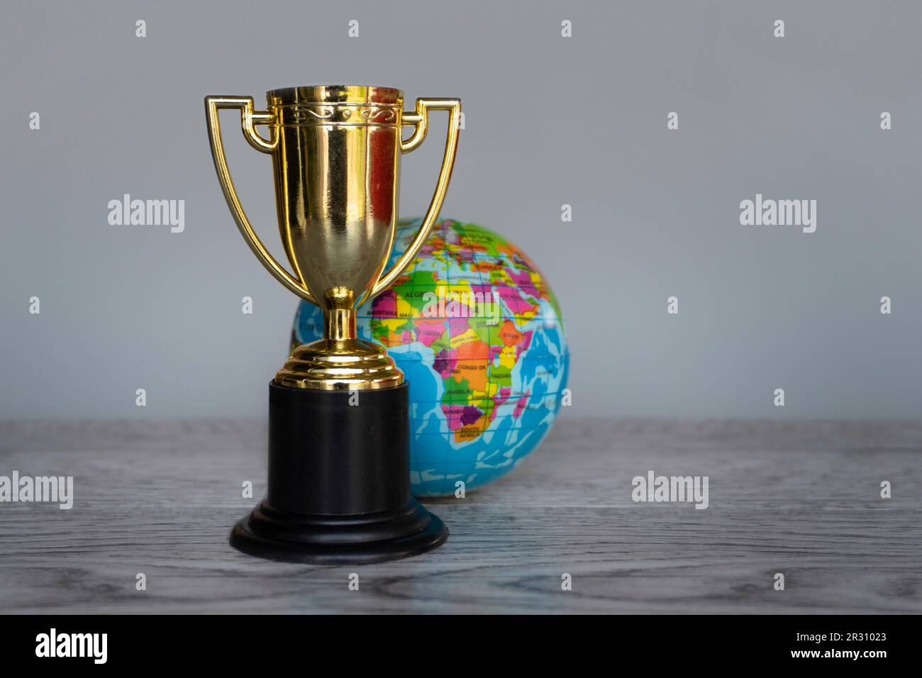Trophée de la coupe d'or et globe terrestre sur table avec espace de copie. Première place, champion du monde, prix, trophées, concept de récompense des gagnants. Banque D'Images