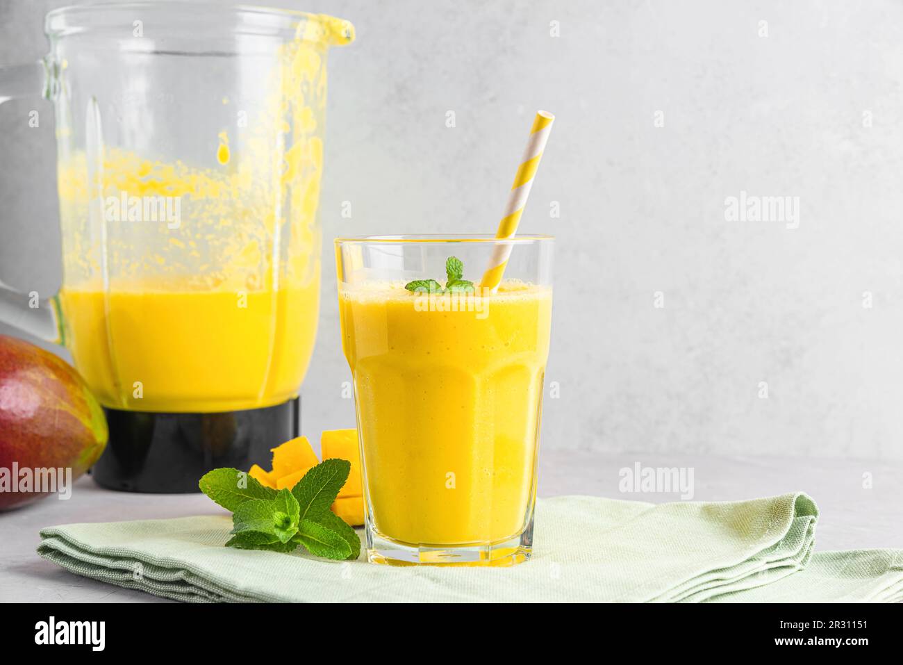 Verre de smoothie à la mangue jaune avec fruits frais juteux et mixeur pour préparer une boisson d'été saine Banque D'Images