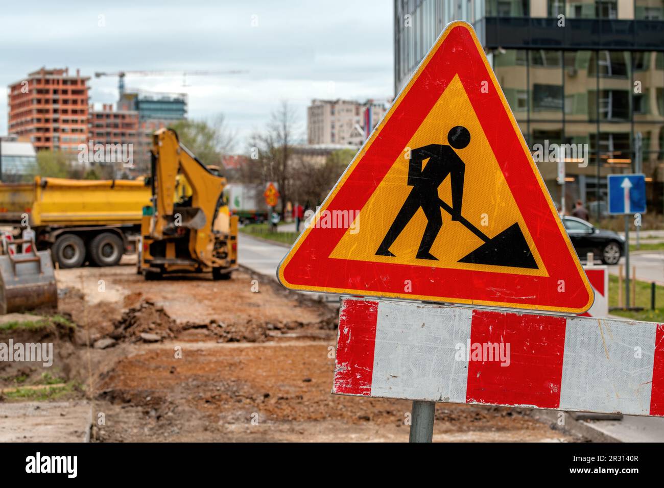 Les hommes au travail signent sur le chantier de construction de travaux routiers et d'entretien des routes avec des camions et des machines en arrière-plan, priorité sélective Banque D'Images