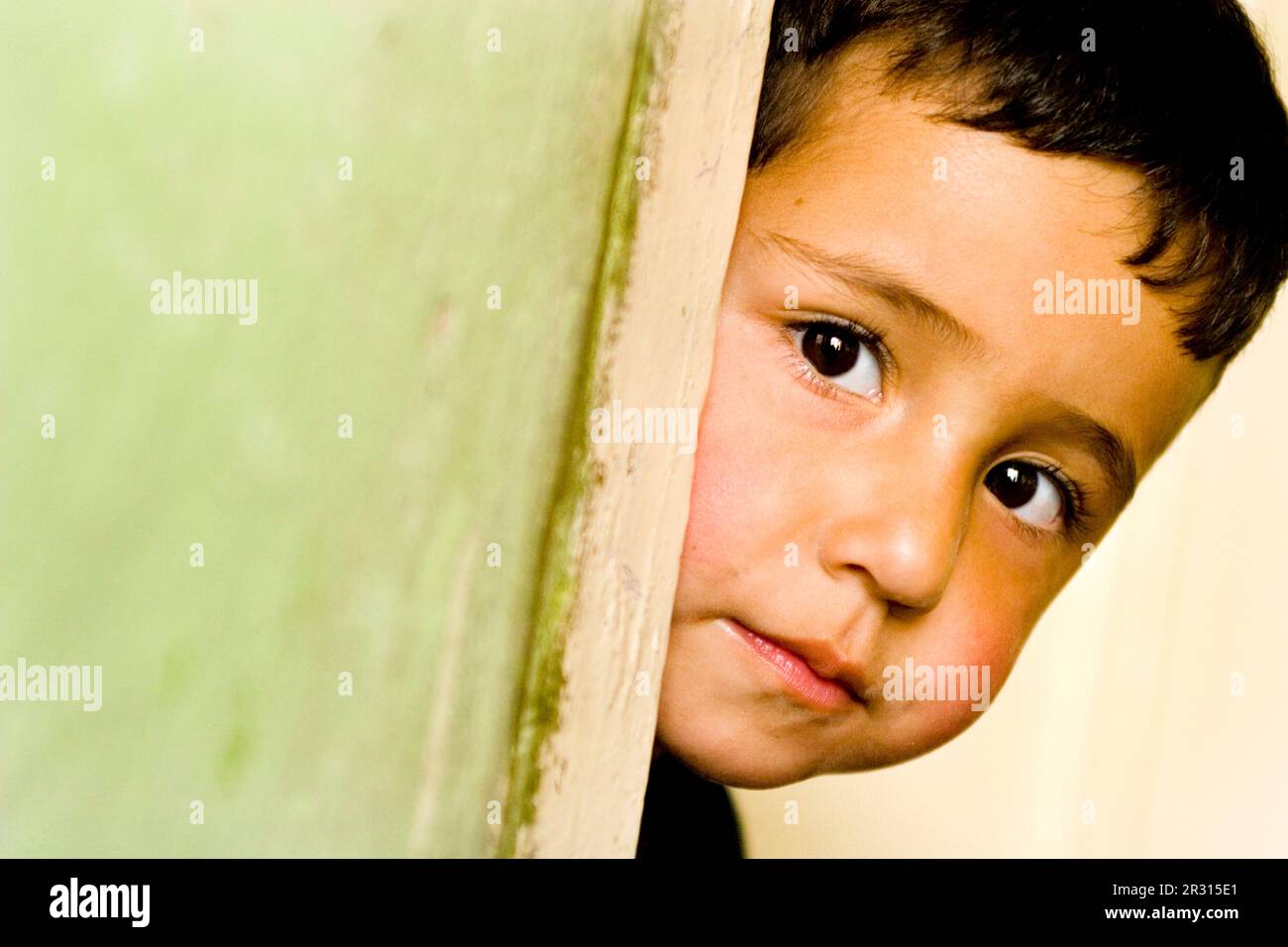 Une jeune fille de quatre ans a la peau derrière une porte à Kaboul. Banque D'Images