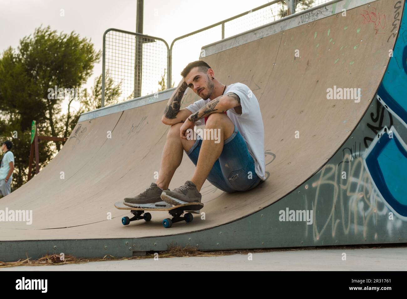 Le jeune homme est sur un terrain de skate avec son skateboard Banque D'Images