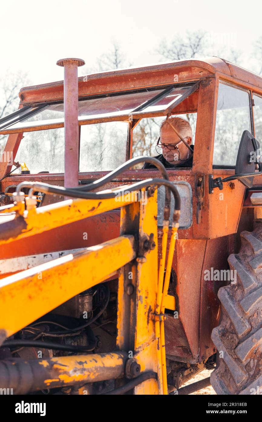 gentleman moderne aux cheveux gris avec des lunettes à bord d'un tracteur Banque D'Images gentleman moderne aux cheveux gris avec des lunettes à bord d'un tracteur Banque D'Images