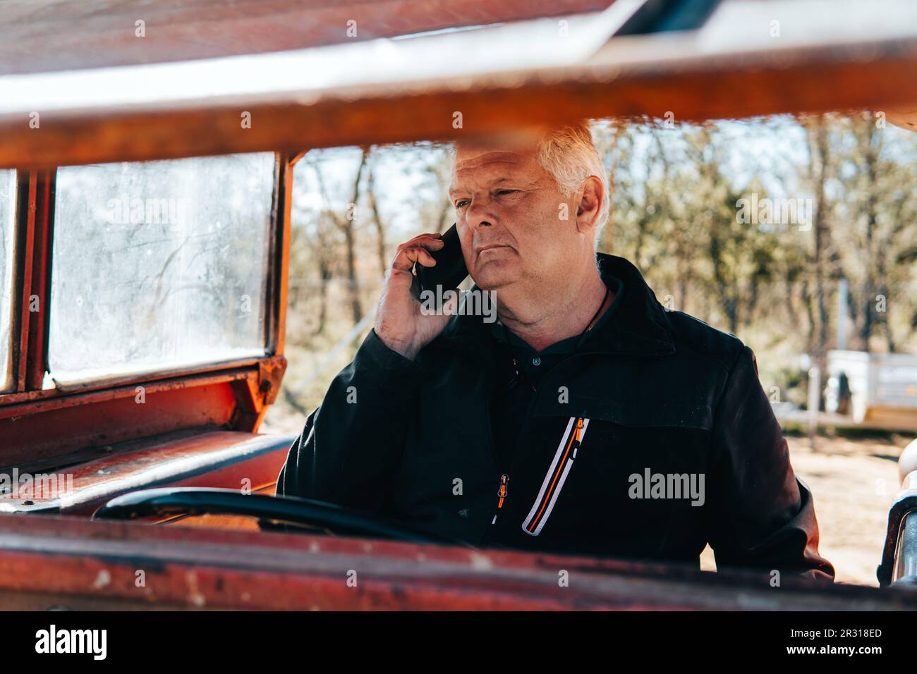 homme moderne plus âgé parlant au téléphone à l'intérieur d'un tracteur Banque D'Images homme moderne plus âgé parlant au téléphone à l'intérieur d'un tracteur Banque D'Images