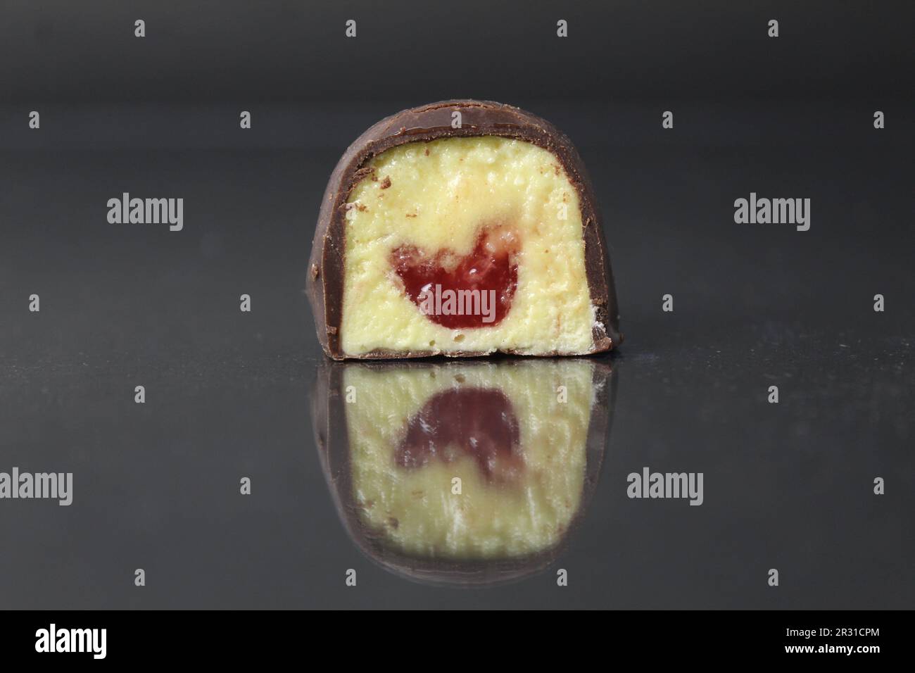 Bonbons de corps de chocolat dans une section, gros plan sur un fond noir, gris, foncé avec une garniture jaune: Fruits: Maango, banane, papaye et baie rouge, ras Banque D'Images