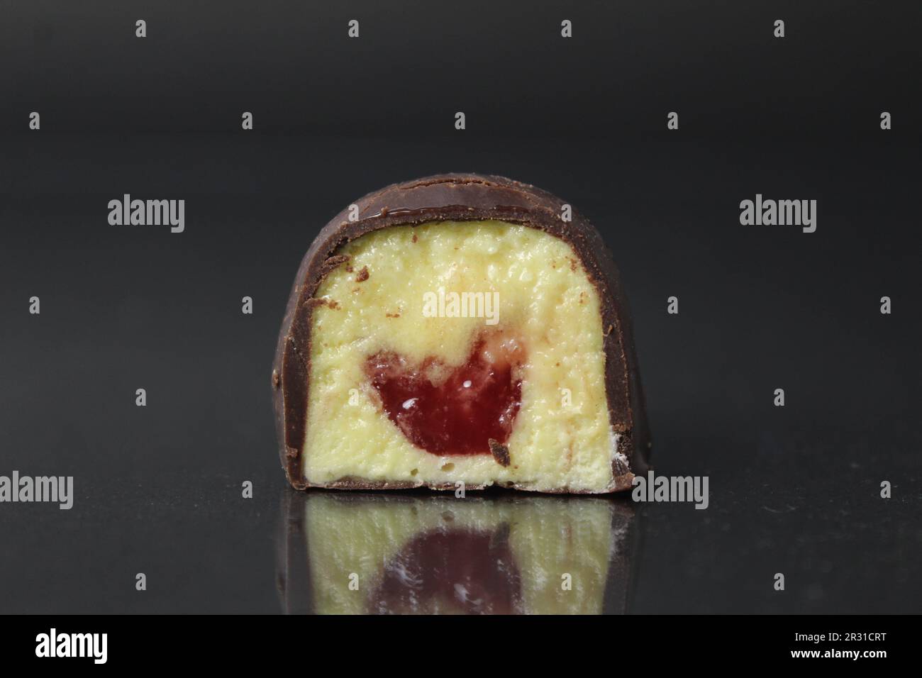 Bonbons de corps de chocolat dans une section, gros plan sur un fond noir, gris, foncé avec une garniture jaune: Fruits: Maango, banane, papaye et baie rouge, ras Banque D'Images