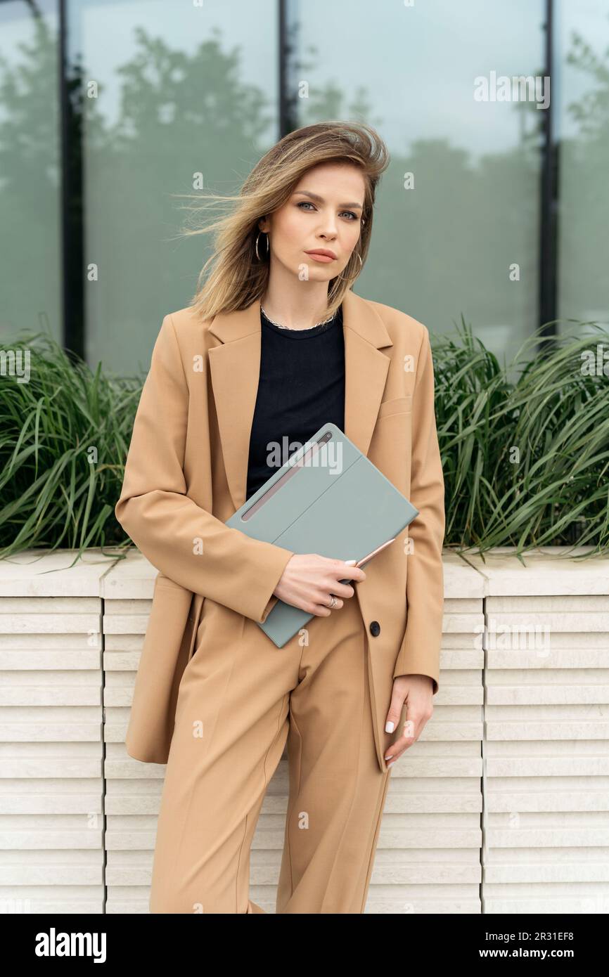 Portrait d'une femme d'affaires élégante dans un costume debout à l'extérieur avec une tablette numérique Banque D'Images