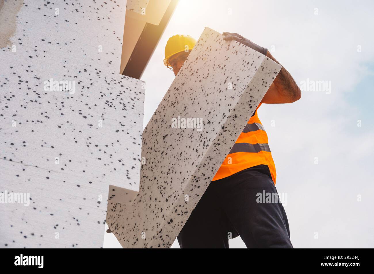 Mason applique de la colle à un revêtement thermique sur un nouveau site de construction Banque D'Images