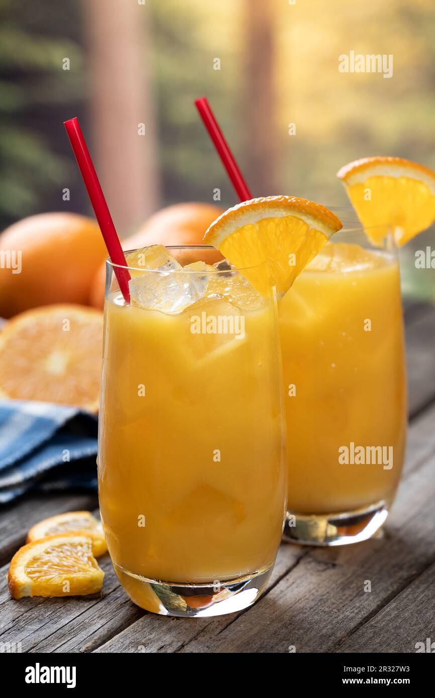 Cocktail de jus d'orange avec des tranches d'orange et des oranges fraîches sur une ancienne table en bois avec fond de nature Banque D'Images