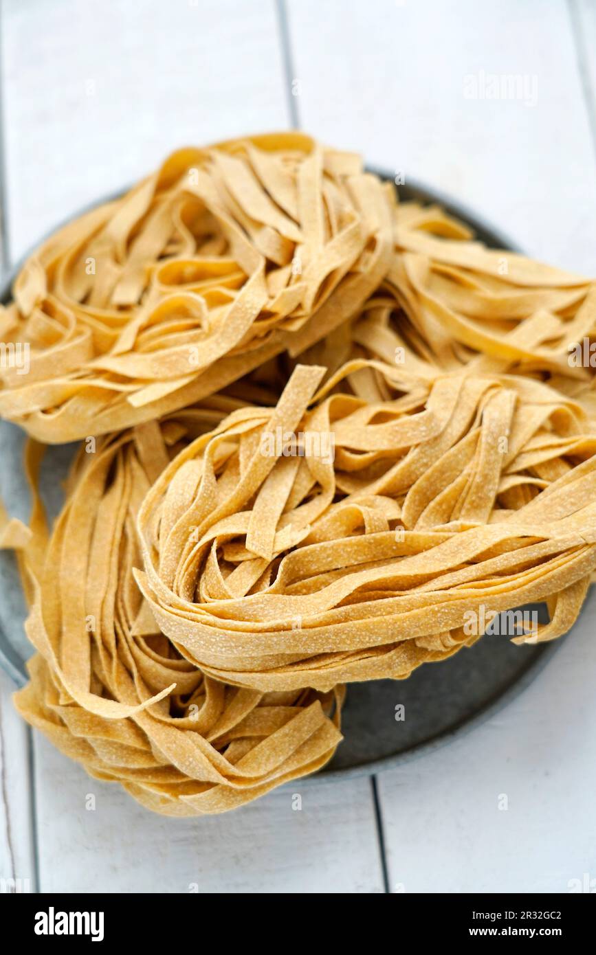 Tagliatelle de blé entier non cuite sur fond de bois blanc, Italie, Europe Banque D'Images