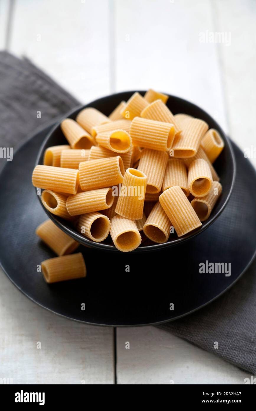 Pâtes de blé entier crues Mezze Maniche sur fond de bois blanc, Italie, Europe Banque D'Images