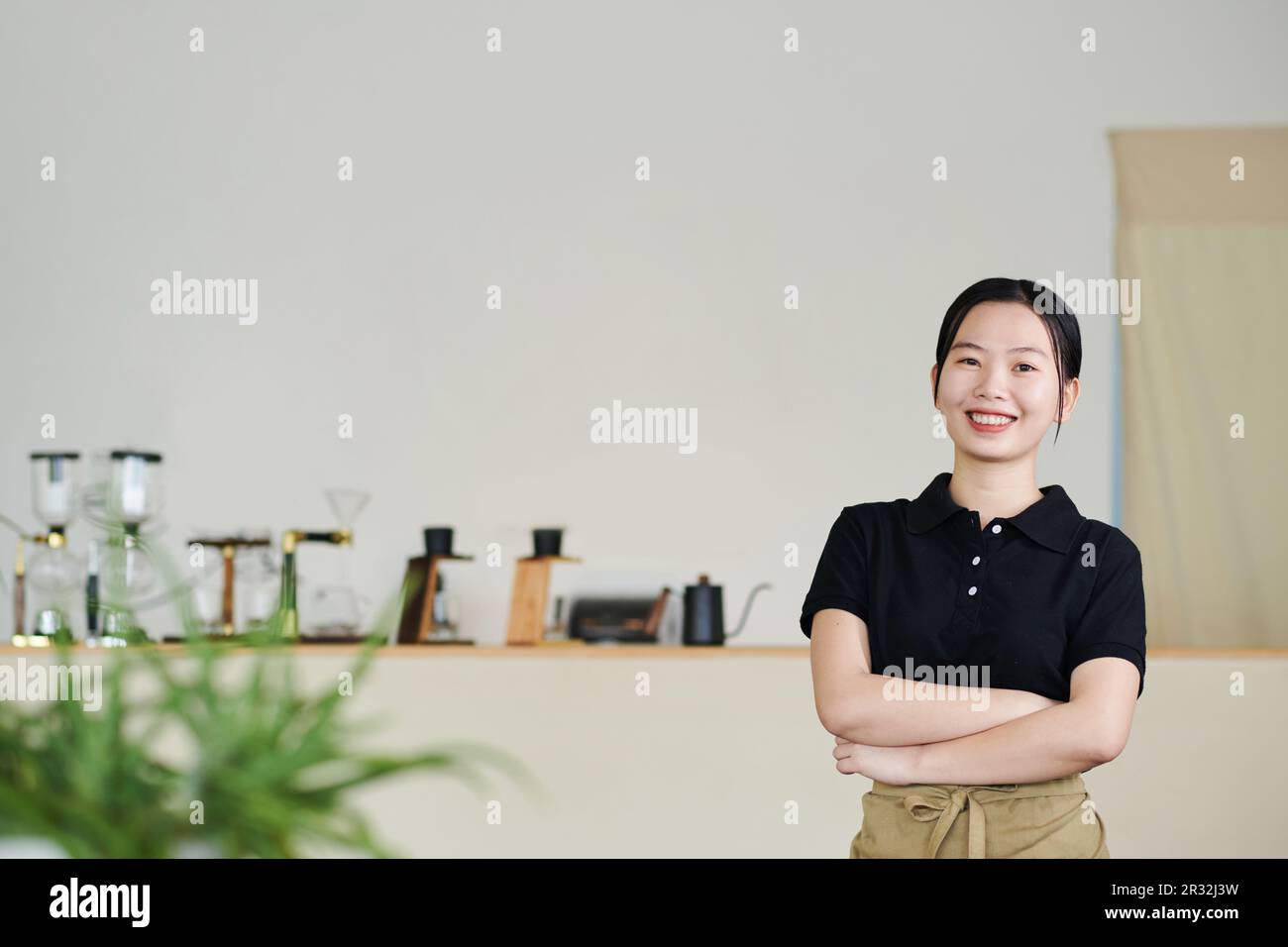 Portrait d'un jeune ouvrier de café heureux croisant les bras et regardant la caméra Banque D'Images