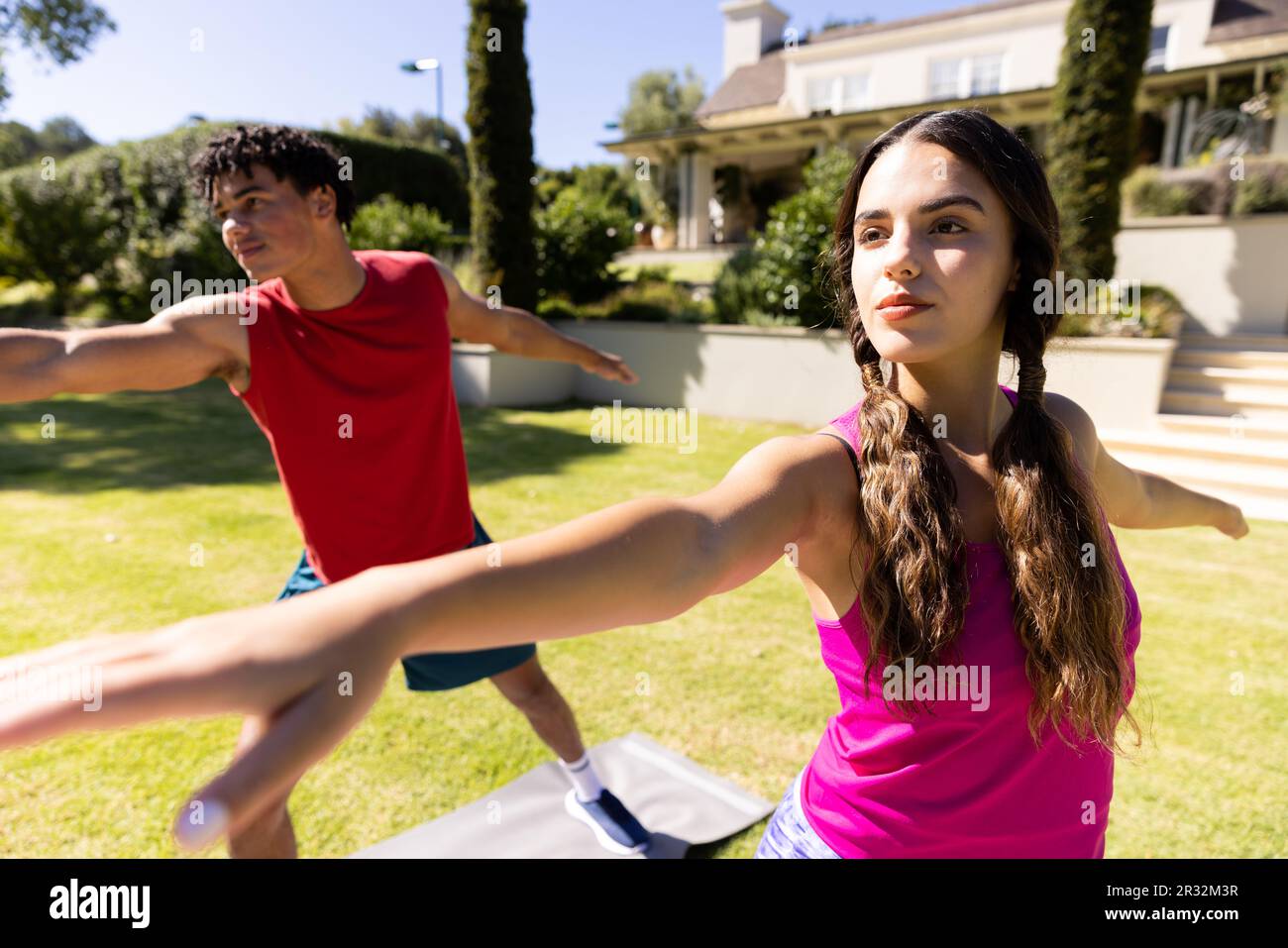 Joyeux couple de forme diverse pratiquant le yoga debout et s'étirant dans le jardin ensoleillé Banque D'Images
