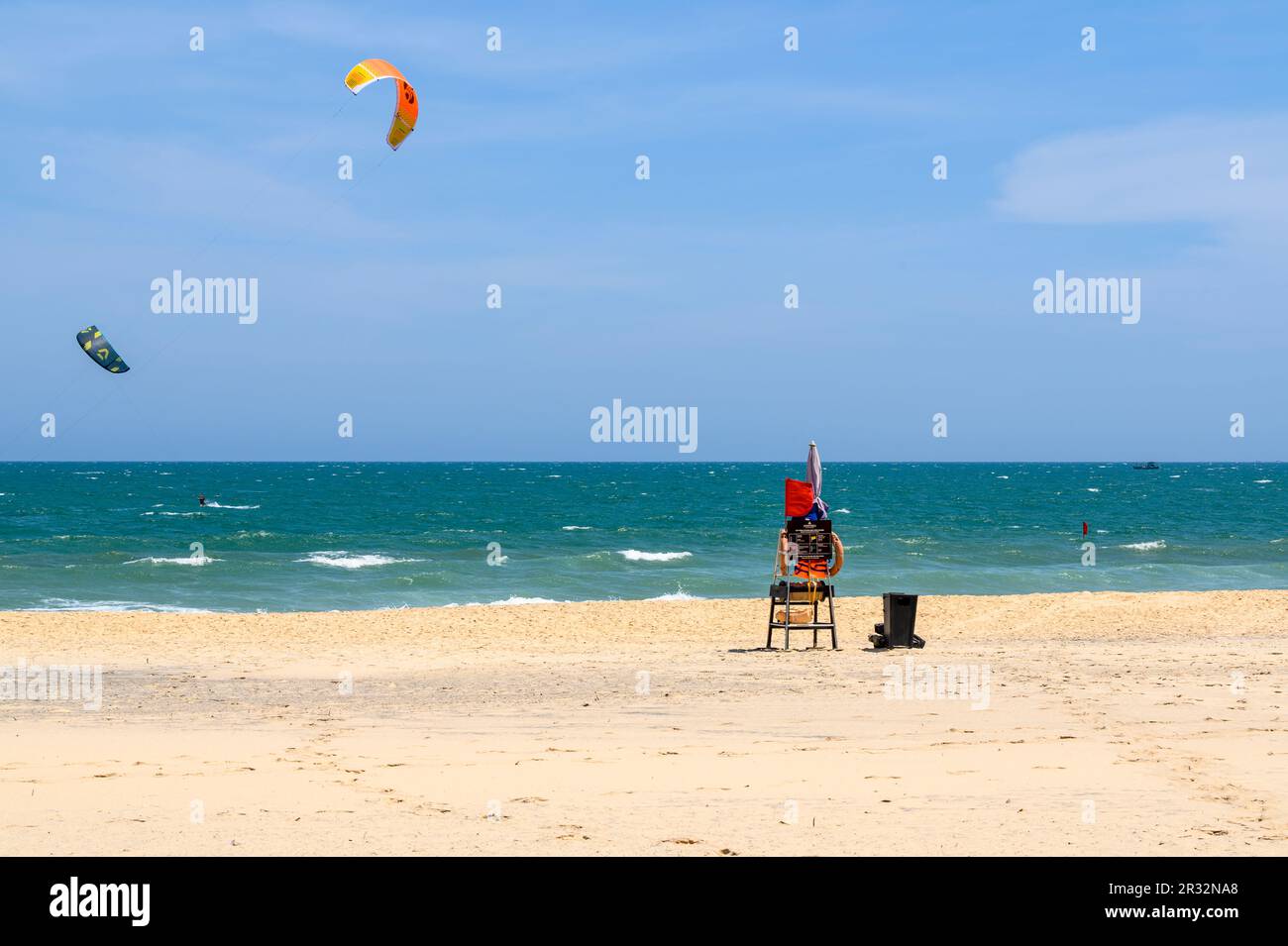 Chaise de maître-nageur sur une plage de sable vide avec des kitesurfers en  action en mer à Mui ne, Vietnam Photo Stock - Alamy