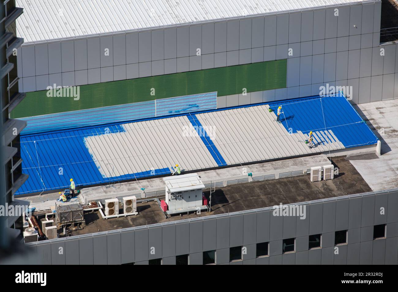 Travailleurs professionnels sur un toit nouvellement installé, les peintres font le travail de peinture pour tourner du blanc au bleu. Banque D'Images