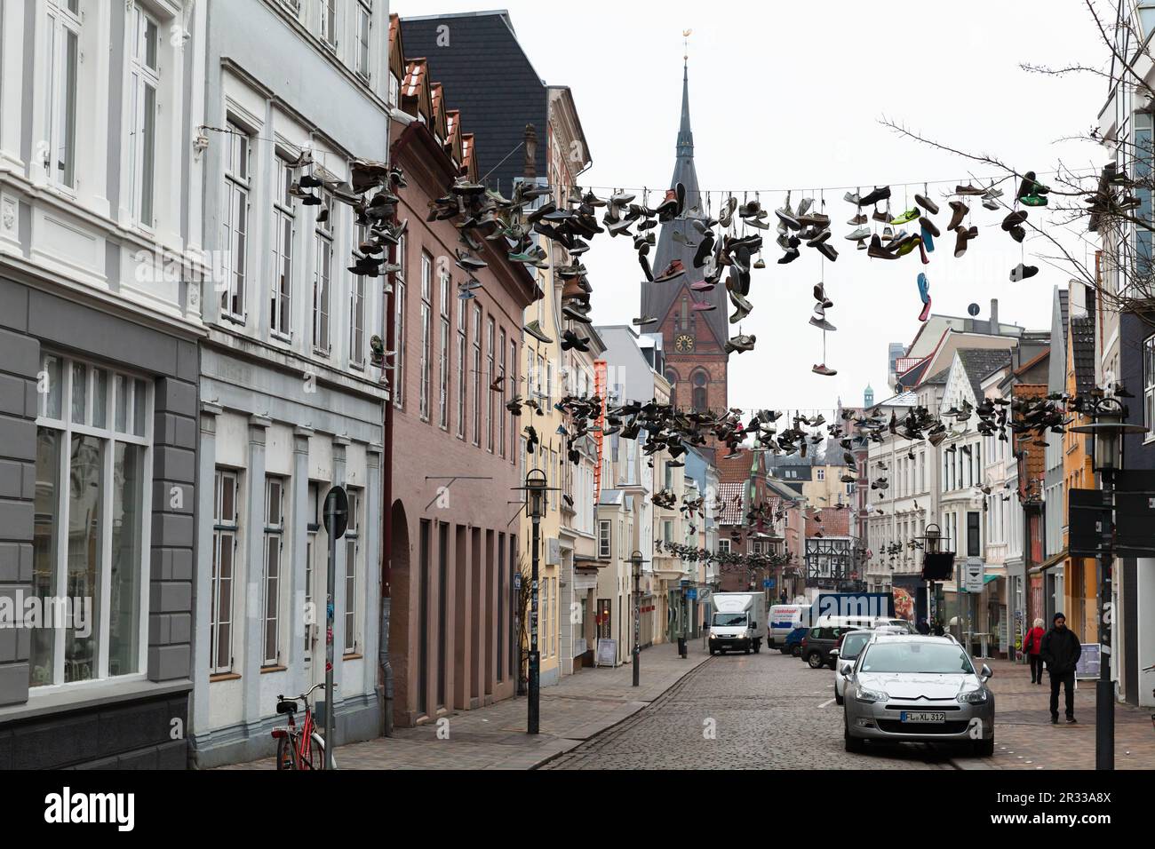 Flensburg, Allemagne - 10 février 2017: Vue sur la rue de Flensburg. De nombreuses chaussures de sport sont accrochées aux fils. Les gens ordinaires marchent dans la rue Banque D'Images