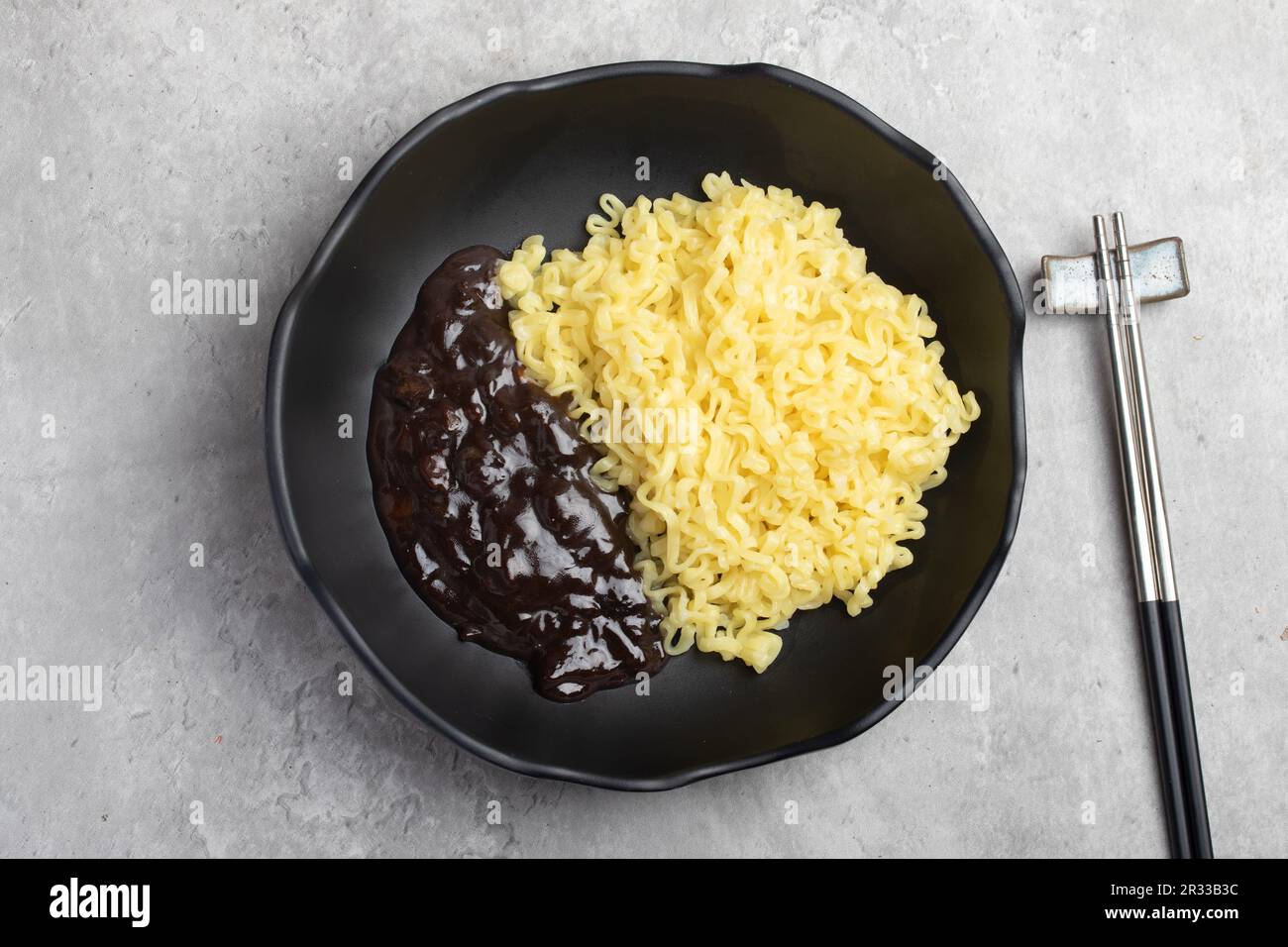 Nouilles instantanées coréennes Jajangmyeon ou Jajangmyeon dans une tasse noire avec sauce noire. Banque D'Images