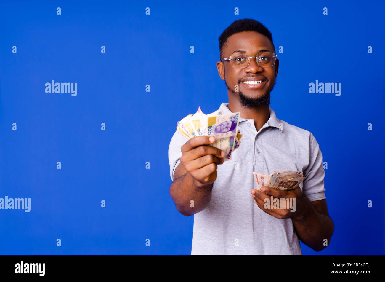Jeune homme africain de bonne apparence recevant de l'argent et souriant Banque D'Images