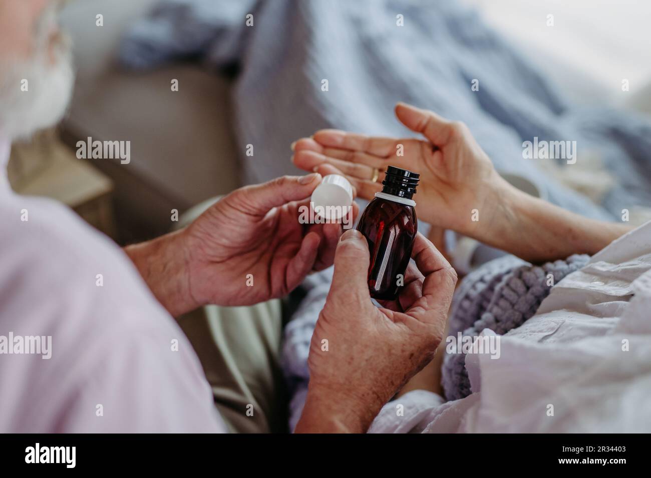 Gros plan sur l'homme âgé qui donne des médicaments à sa femme malade. Banque D'Images