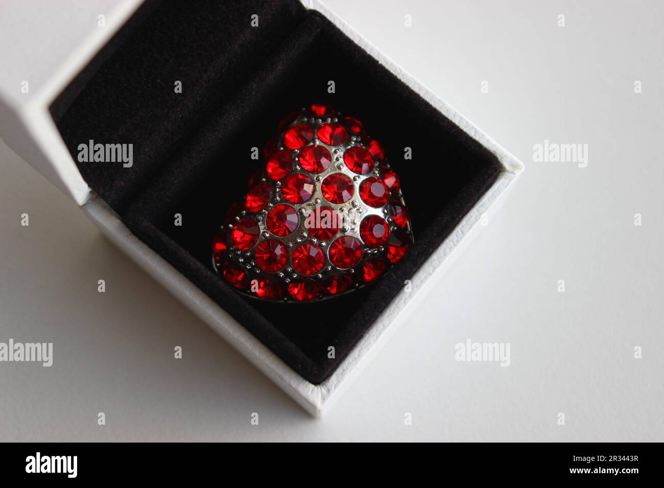 Bijoux en forme de coeur avec des pierres précieuses rouges dans une boîte cadeau isolé sur blanc Banque D'Images