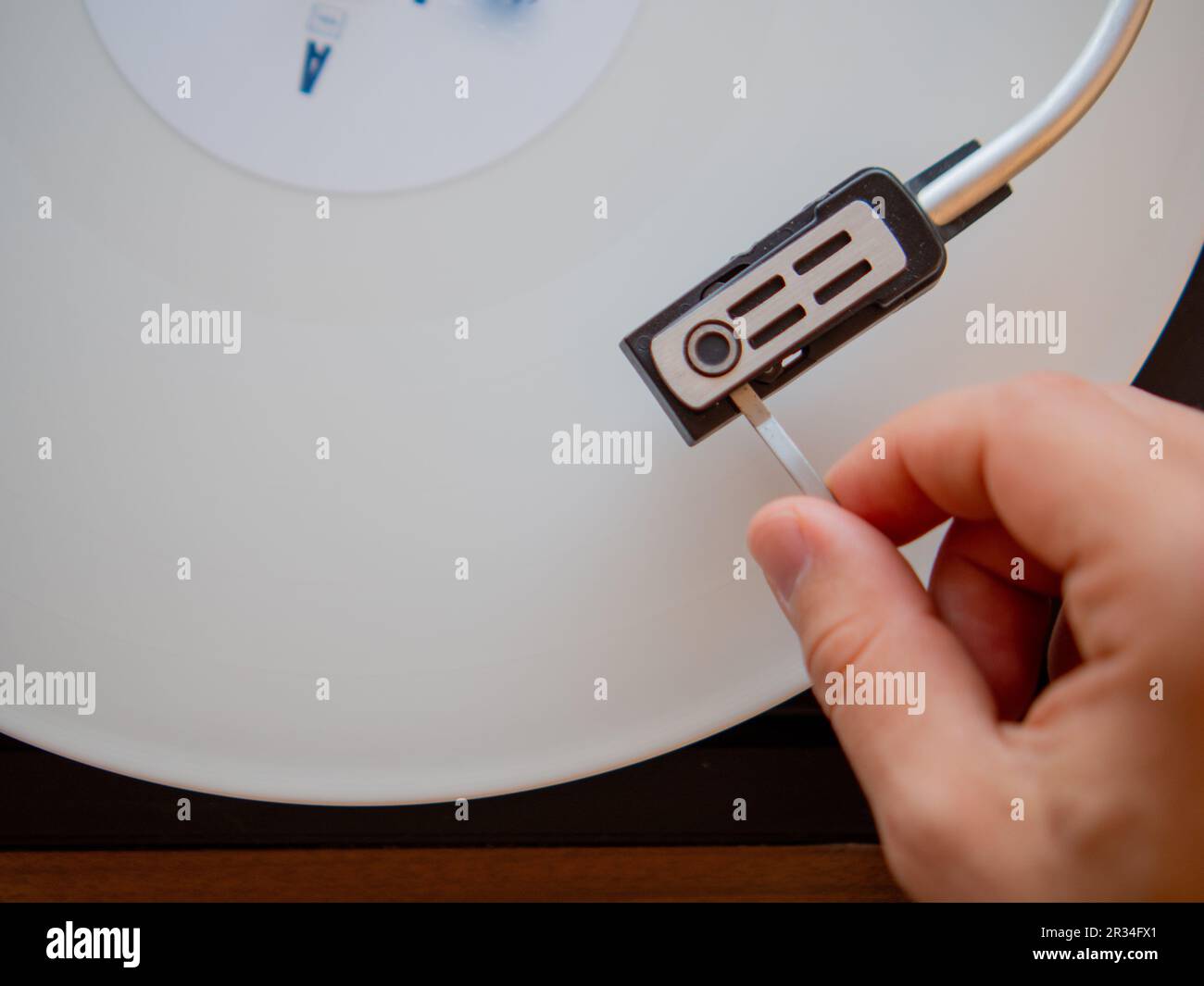 Détail d'une main masculine plaçant l'aiguille sur la piste d'un disque en vinyle blanc. Plateau tournant vintage Banque D'Images