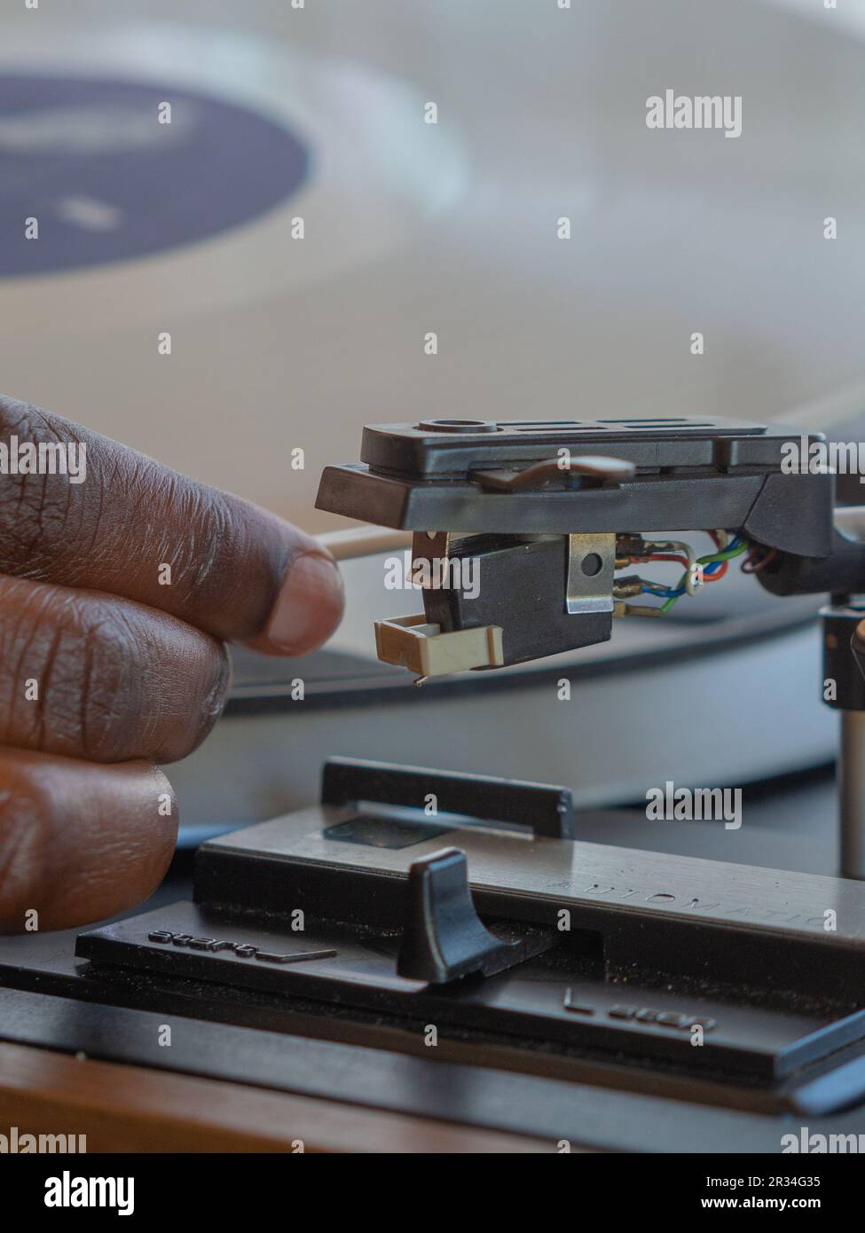Détail d'une main féminine plaçant un disque en vinyle blanc sur une platine vintage Banque D'Images