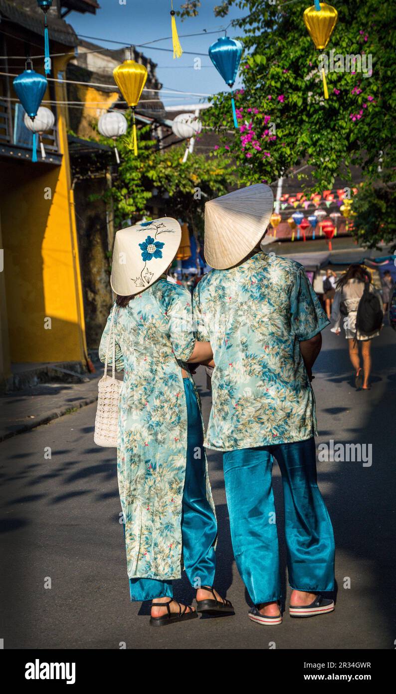 La vue arrière d'un couple portant des robes traditionnelles vietnamiennes marchant à Hoi an vieille ville. Banque D'Images