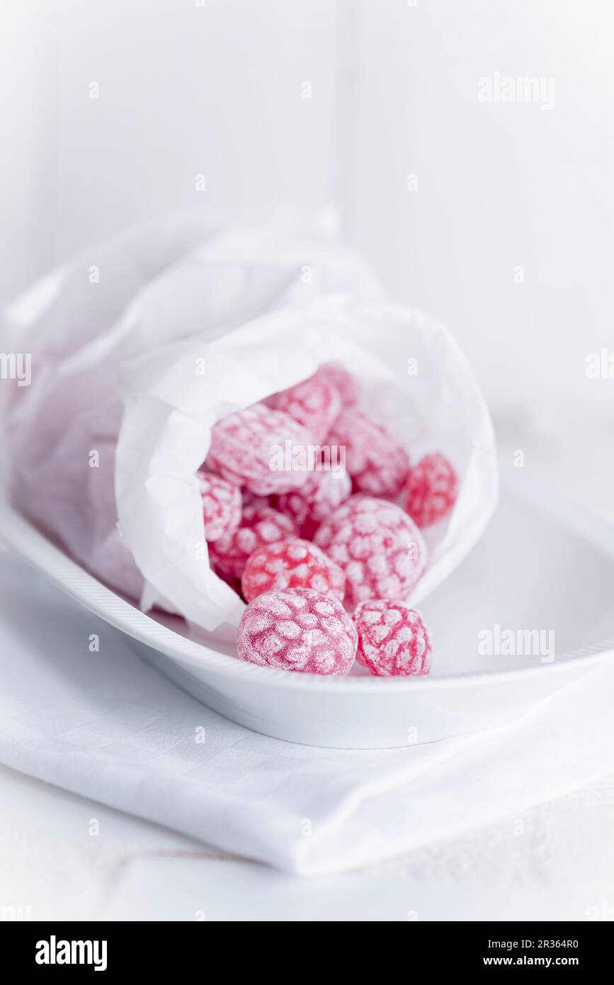 Bonbons à la framboise dans un sac de pain sur un plat blanc Banque D'Images