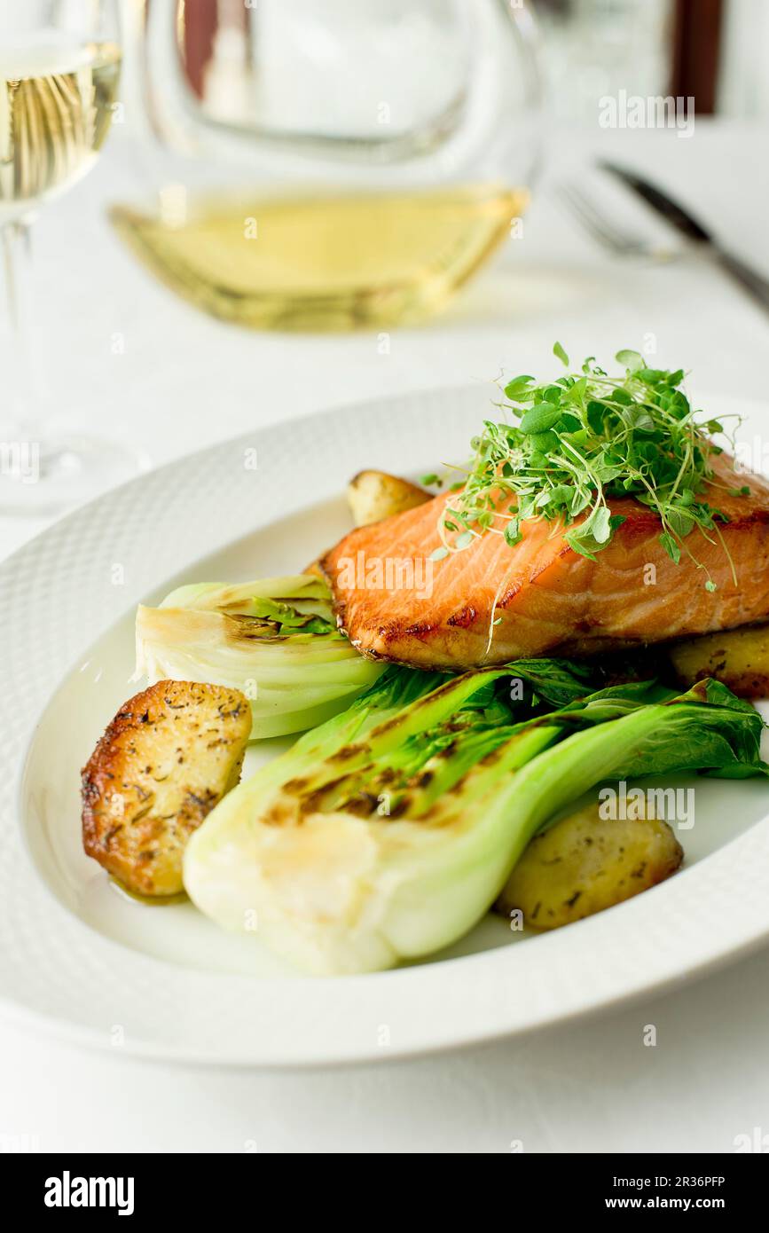 Saumon sur le pak choy grillé et pommes de terre frites Banque D'Images