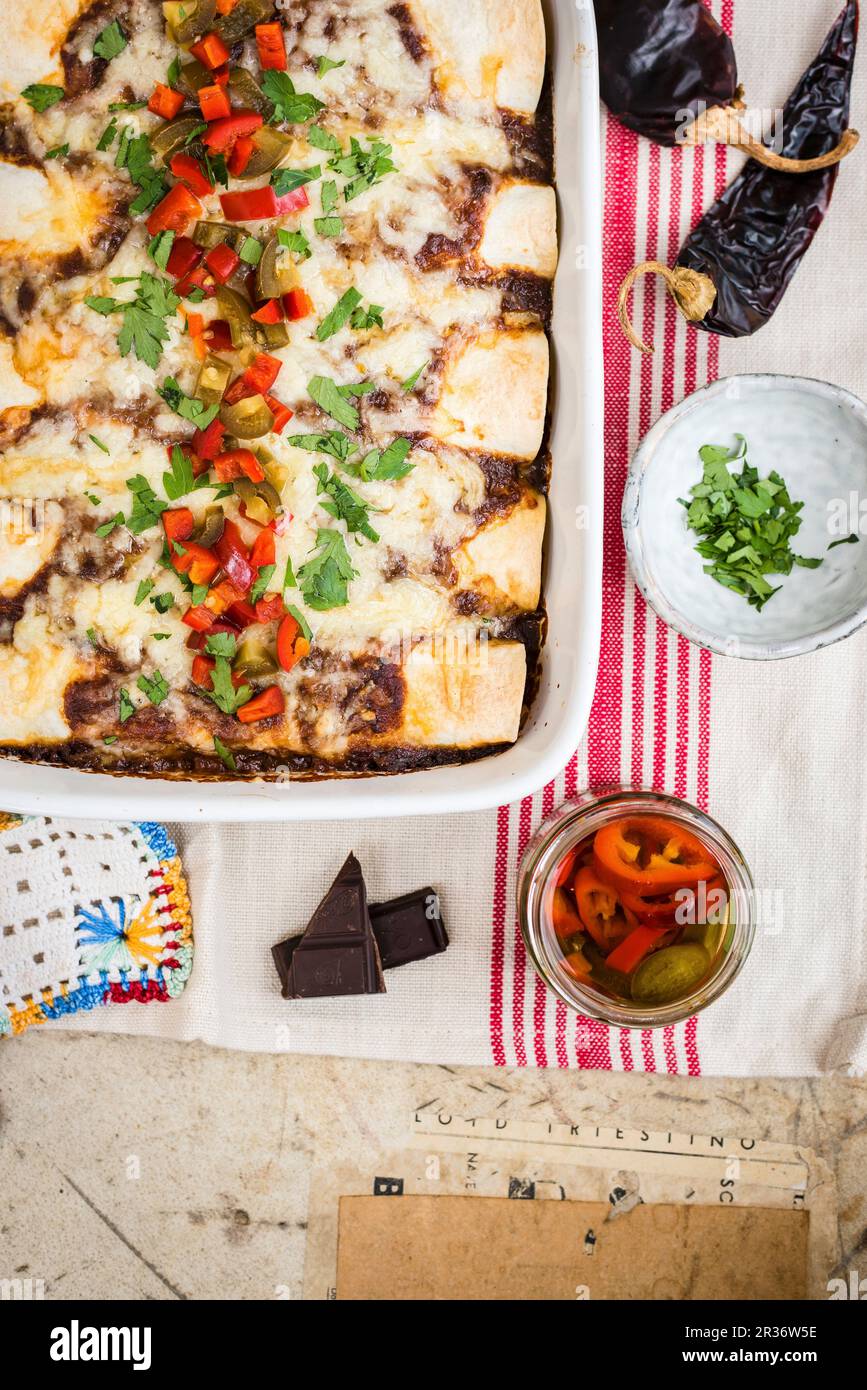 Enchiladas avec sauce au porc et à la mole dans un plat de cuisson avec des jalapenos marinés Banque D'Images