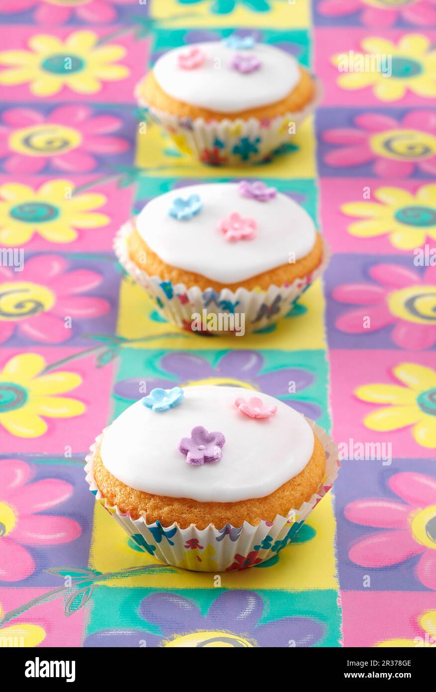 Trois gâteaux Fée assis sur un fond de fleurs colorées Banque D'Images