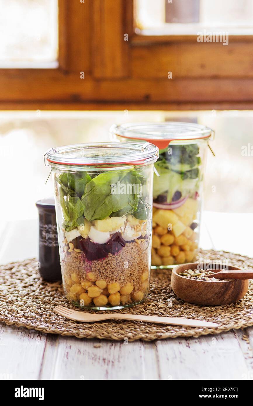 Deux salades dans les pots préparés dans un service de buffet pour un brunch avec un mélange de graines pour s'habiller Banque D'Images