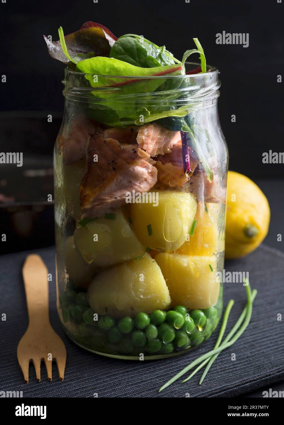 Saumon à la vapeur et les pommes de terre dans un bocal en verre avec des petits pois et Chard Banque D'Images