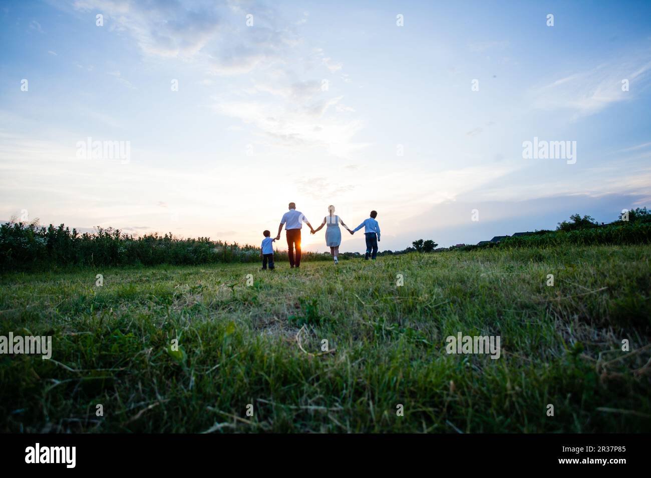 Famille heureuse sur l'arrière-plan de la coucher du soleil Banque D'Images