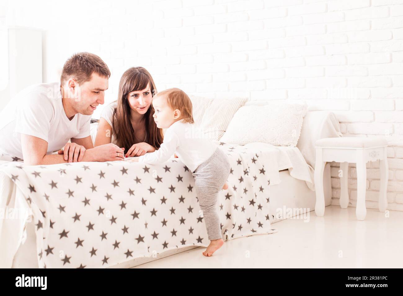 Les parents à enseigner à l'enfant de grimper sur le lit Banque D'Images