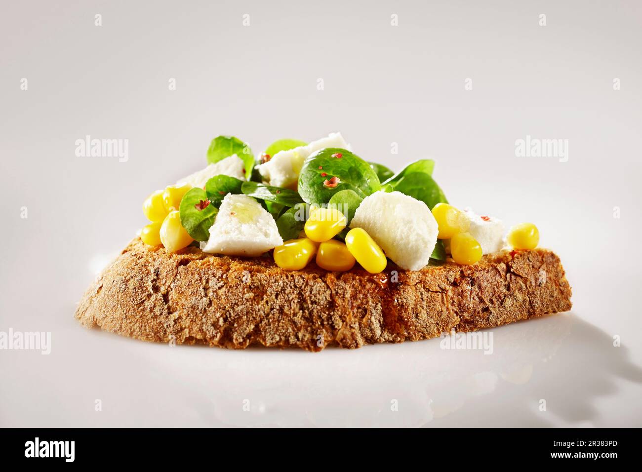 Un sandwich ouvert sur du pain de ferme avec de la laitue d'agneau, du maïs sucré et du poivre rose Banque D'Images